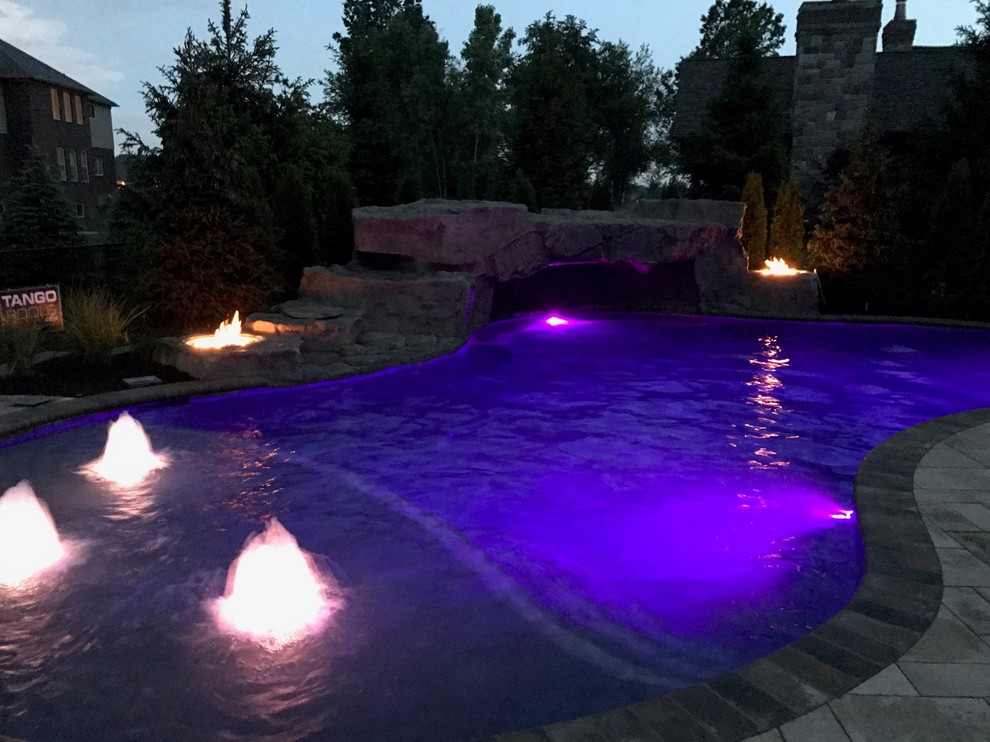 Стильный дизайн: огромный бассейн-инфинити произвольной формы на заднем дворе в стиле модернизм с покрытием из каменной брусчатки - последний тренд