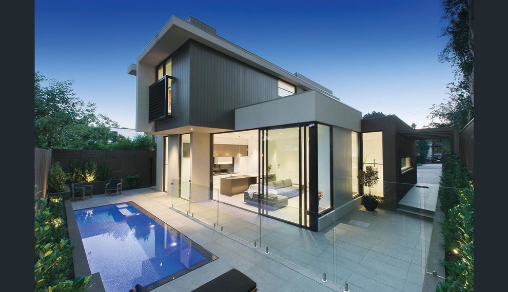 Modelo de piscina alargada minimalista de tamaño medio rectangular en patio trasero con adoquines de piedra natural