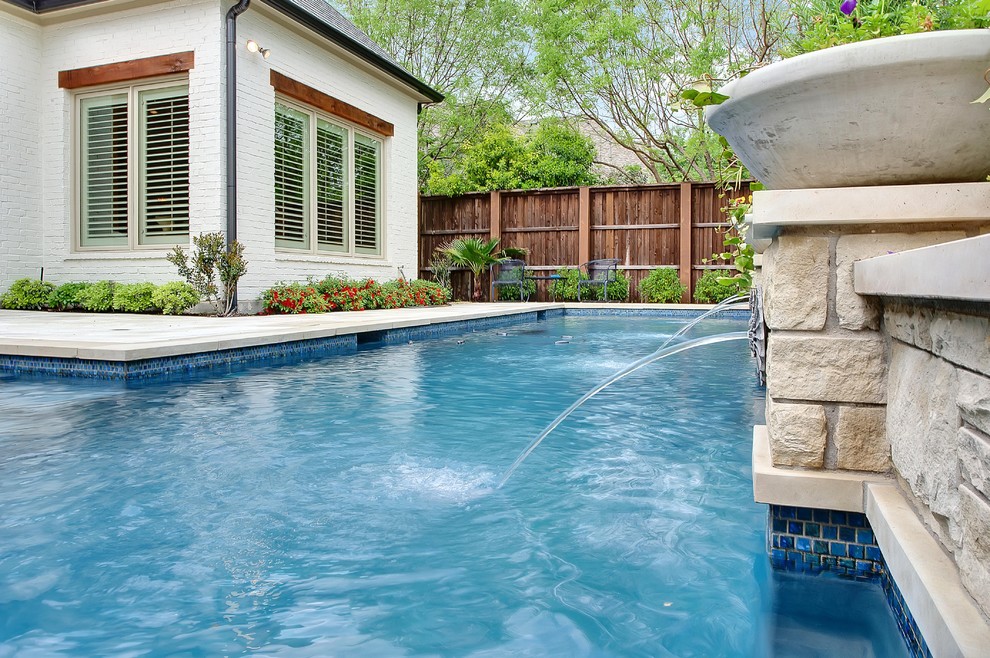 Modelo de piscina con fuente natural tradicional de tamaño medio a medida en patio trasero con losas de hormigón