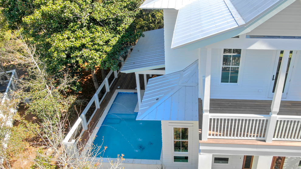 Diseño de piscina con fuente alargada marinera grande rectangular en patio lateral con entablado