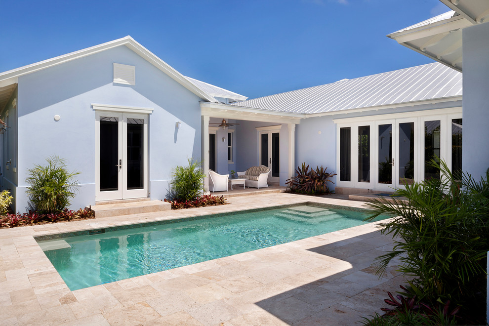 Diseño de piscina alargada costera extra grande rectangular en patio trasero con adoquines de piedra natural