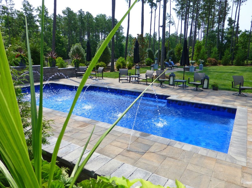 Aménagement d'une très grande piscine arrière classique avec un point d'eau et des pavés en béton.