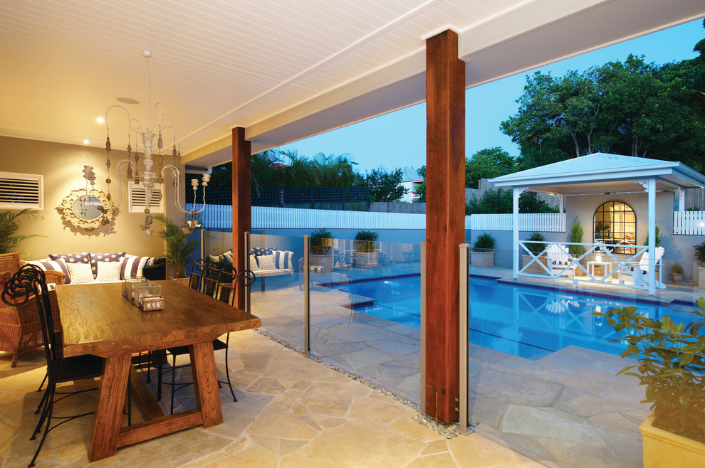 Medium sized traditional back rectangular natural swimming pool in Brisbane with a pool house and natural stone paving.