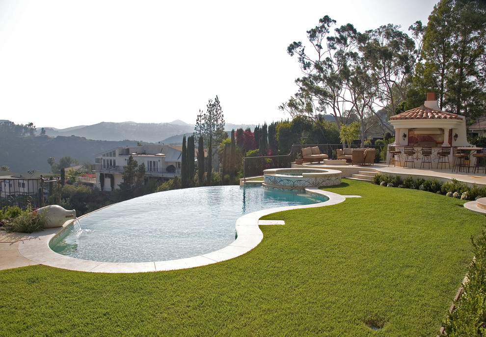 Ejemplo de piscina infinita mediterránea grande tipo riñón en patio trasero con suelo de baldosas