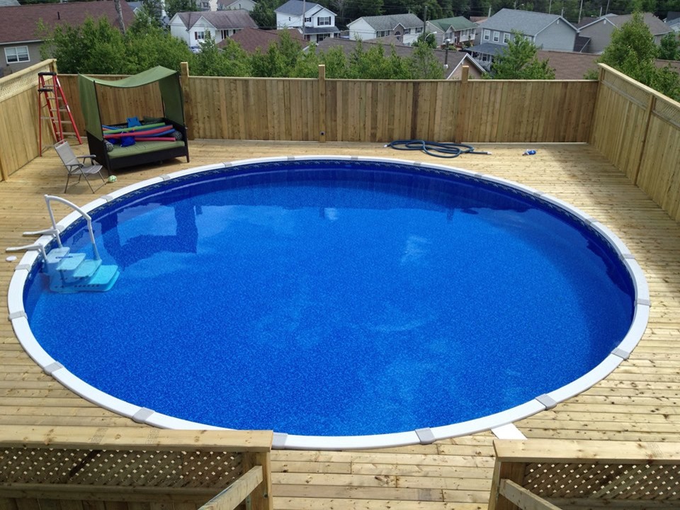 Ejemplo de piscina redondeada en patio trasero con entablado
