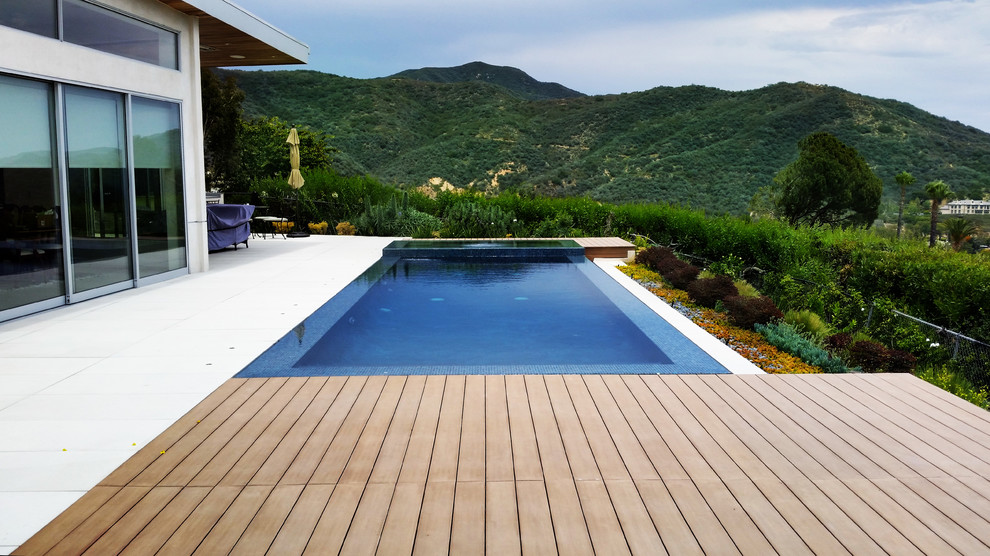 Ejemplo de piscinas y jacuzzis minimalistas de tamaño medio rectangulares en patio trasero con adoquines de hormigón