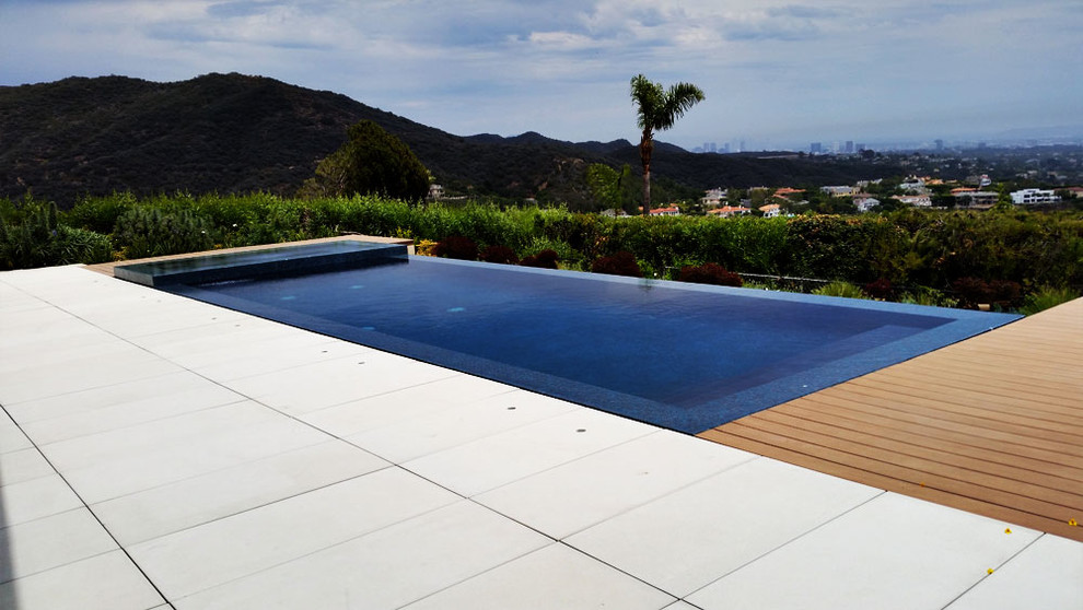 Diseño de piscinas y jacuzzis infinitos minimalistas de tamaño medio rectangulares en patio trasero con adoquines de hormigón
