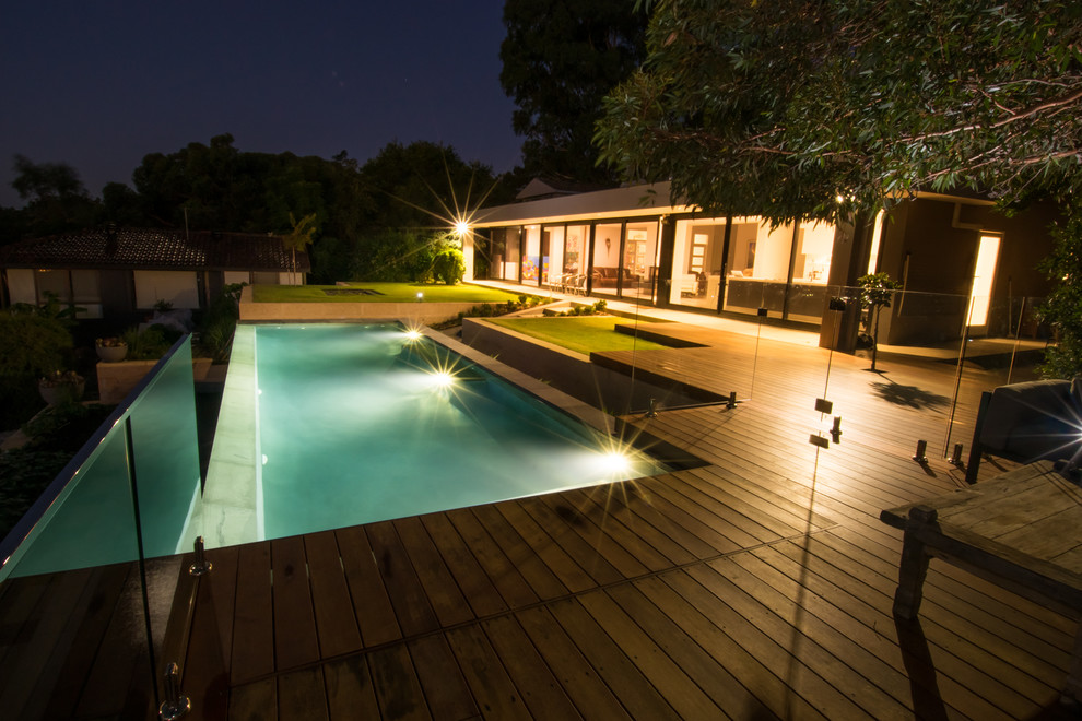 Idée de décoration pour une piscine à débordement et arrière rectangle et de taille moyenne avec un point d'eau et une terrasse en bois.