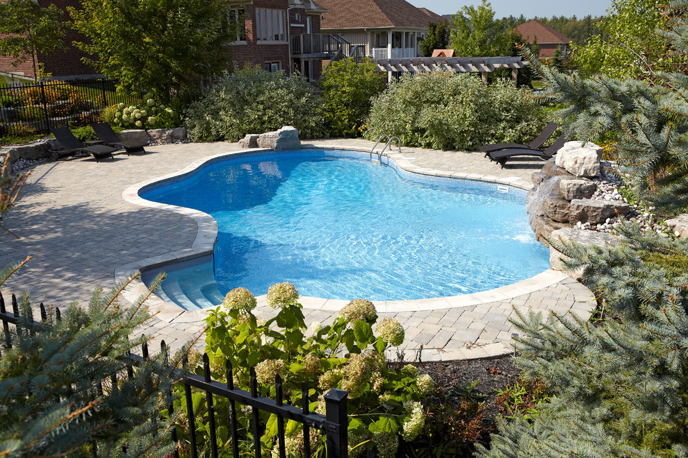 Imagen de piscina con fuente natural actual grande a medida en patio trasero con adoquines de ladrillo