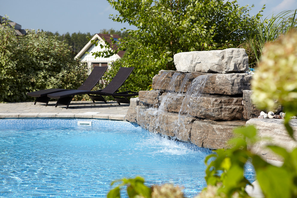 Imagen de piscina con fuente natural actual grande a medida en patio trasero con adoquines de ladrillo