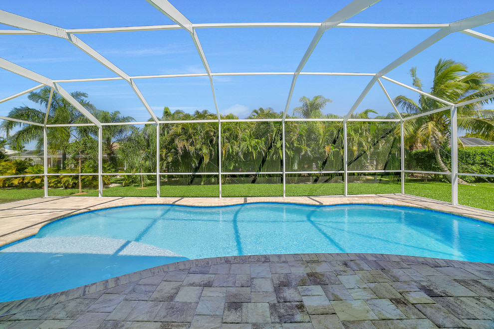 Esempio di una piscina tradizionale a "C" di medie dimensioni e dietro casa con pavimentazioni in mattoni