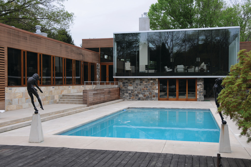 Ispirazione per una grande piscina naturale moderna rettangolare dietro casa con lastre di cemento