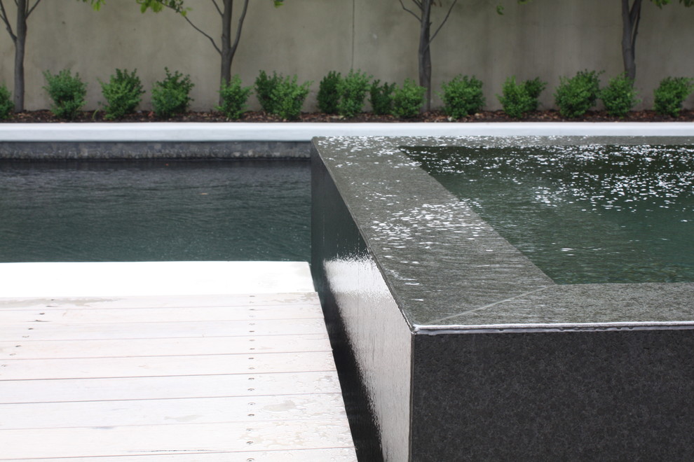 Aménagement d'une piscine arrière contemporaine de taille moyenne et rectangle avec une terrasse en bois.