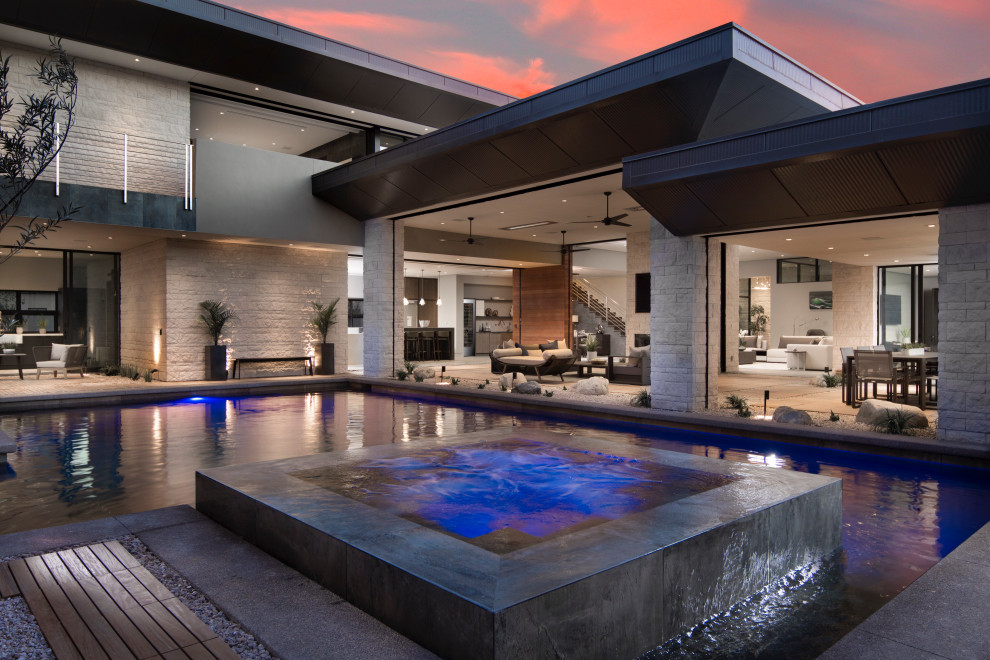 Esempio di una grande piscina design a "L" dietro casa con una vasca idromassaggio e piastrelle