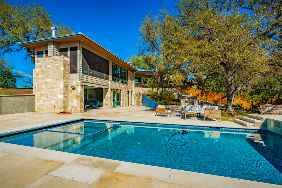 Ejemplo de piscinas y jacuzzis clásicos grandes rectangulares en patio trasero con adoquines de piedra natural