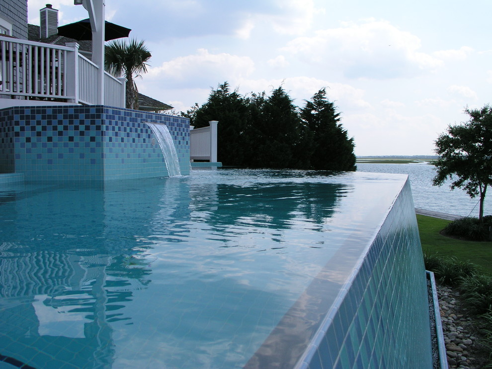 Esempio di una piscina a sfioro infinito design personalizzata dietro casa con una vasca idromassaggio
