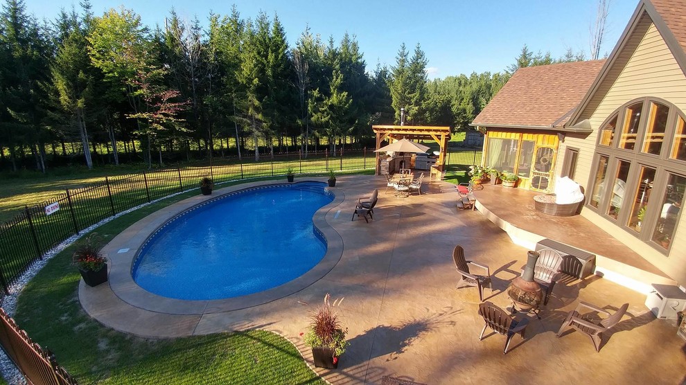 Ispirazione per una grande piscina stile rurale a "C" dietro casa con cemento stampato