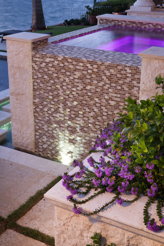 На фото: прямоугольный бассейн-инфинити на заднем дворе в средиземноморском стиле с джакузи и покрытием из каменной брусчатки с