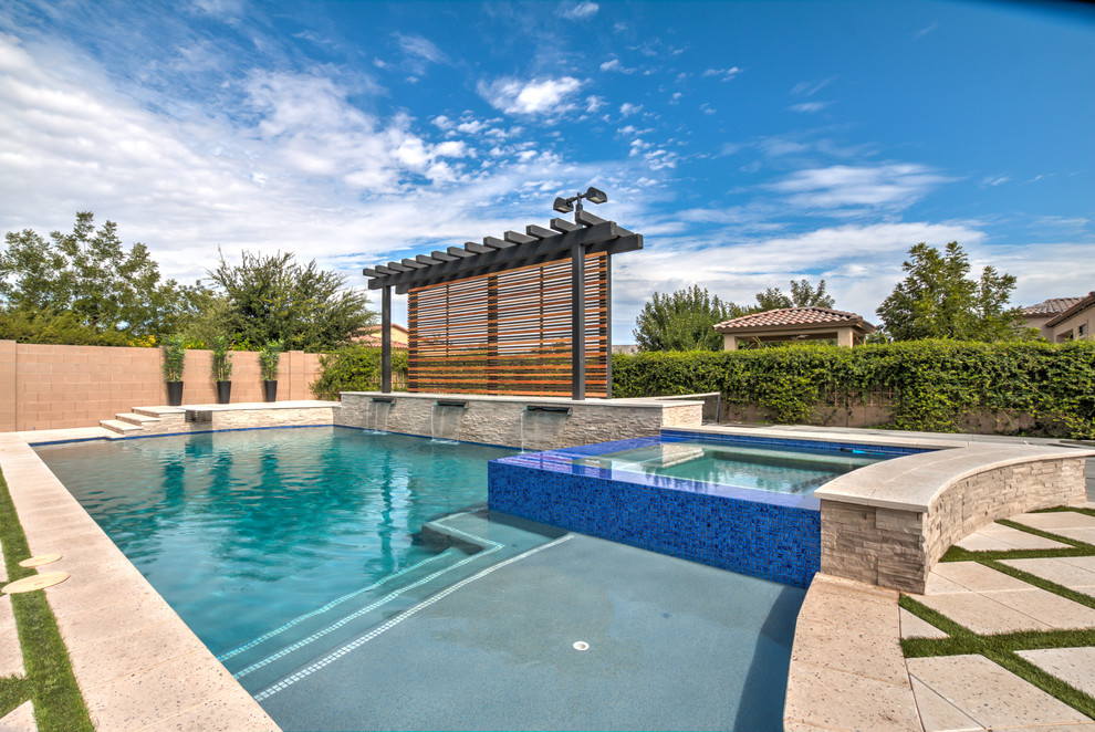 Ejemplo de piscina con fuente alargada mediterránea grande a medida en patio trasero con adoquines de hormigón