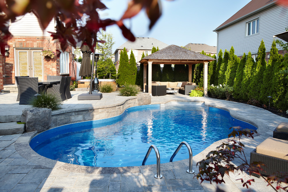 Großer Moderner Schwimmteich hinter dem Haus in individueller Form mit Wasserspiel und Natursteinplatten in Toronto
