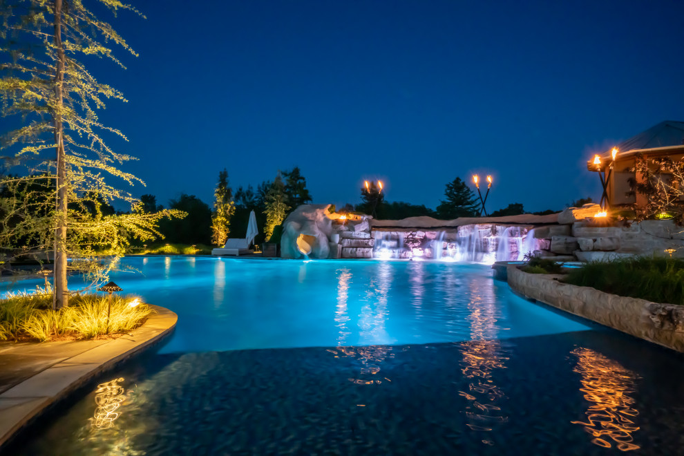 Foto de piscina natural de estilo de casa de campo extra grande a medida en patio trasero con privacidad y adoquines de piedra natural