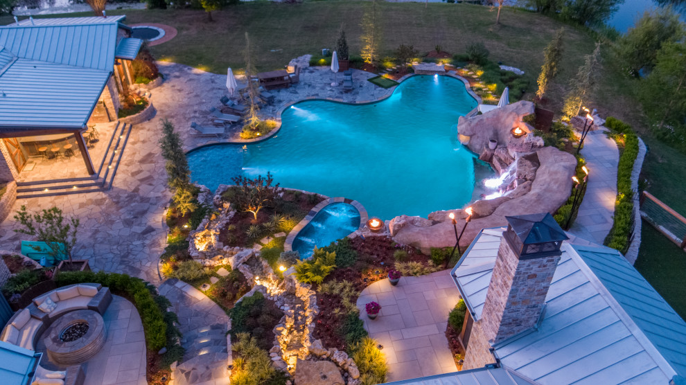 Expansive rural back custom shaped natural swimming pool in Oklahoma City with with pool landscaping and natural stone paving.