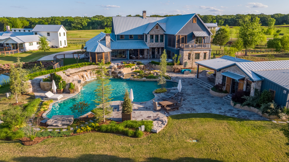 Huge country backyard stone and custom-shaped natural pool landscaping photo in Oklahoma City