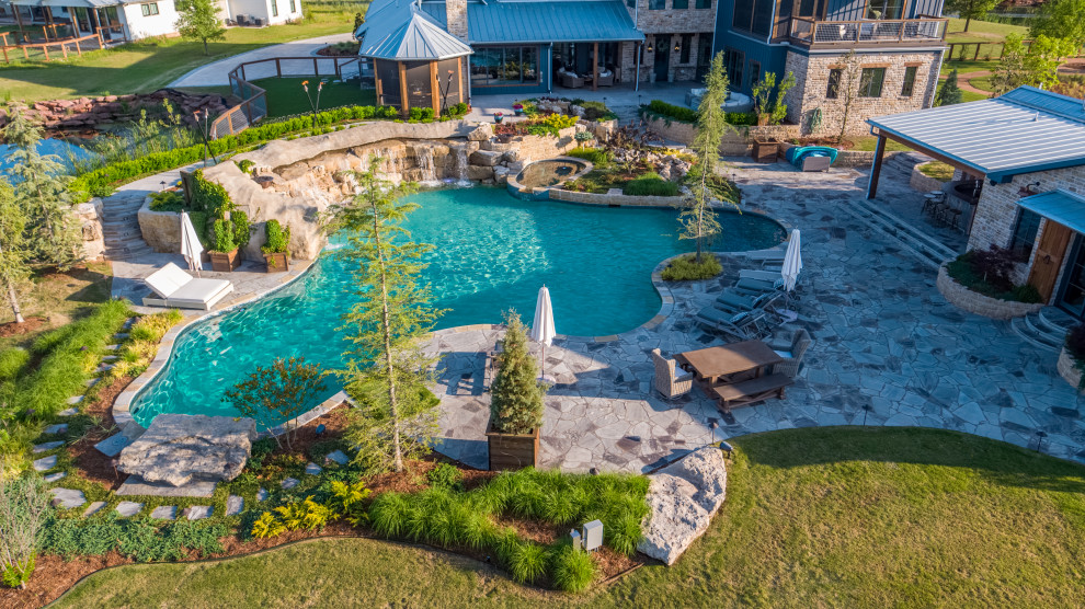 Ejemplo de piscina natural de estilo de casa de campo extra grande a medida en patio trasero con paisajismo de piscina y adoquines de piedra natural