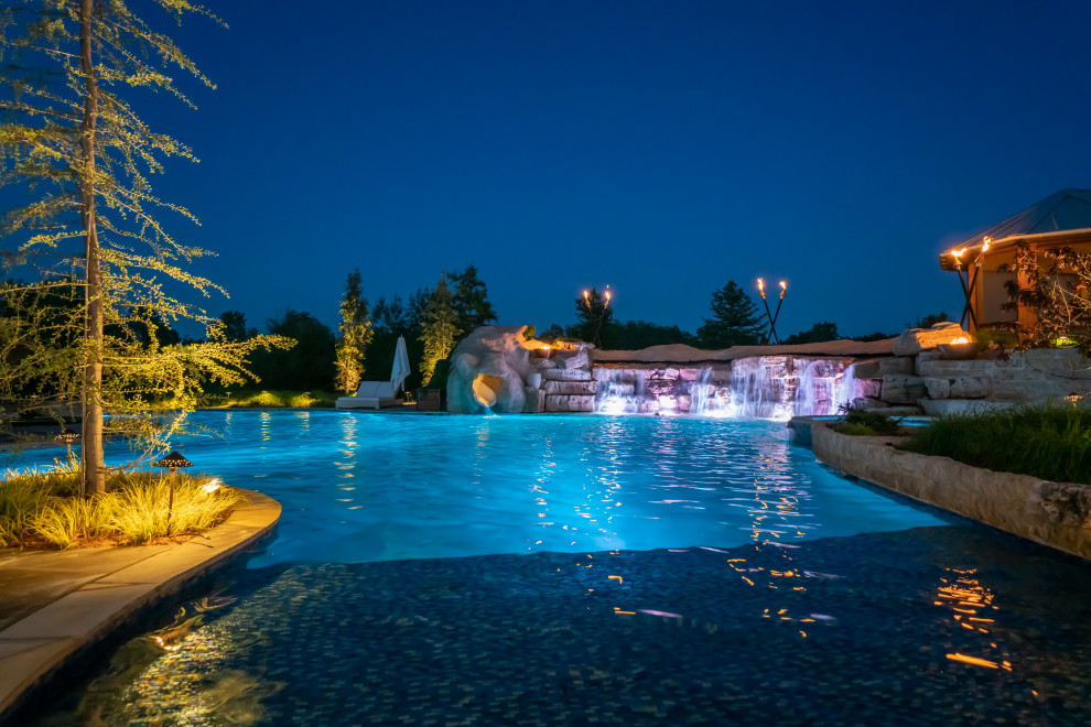 Foto de piscina natural de estilo de casa de campo extra grande a medida en patio trasero con privacidad y adoquines de piedra natural