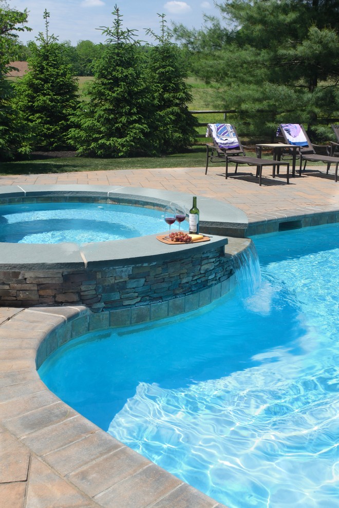Foto de piscinas y jacuzzis clásicos de tamaño medio a medida en patio trasero con adoquines de hormigón