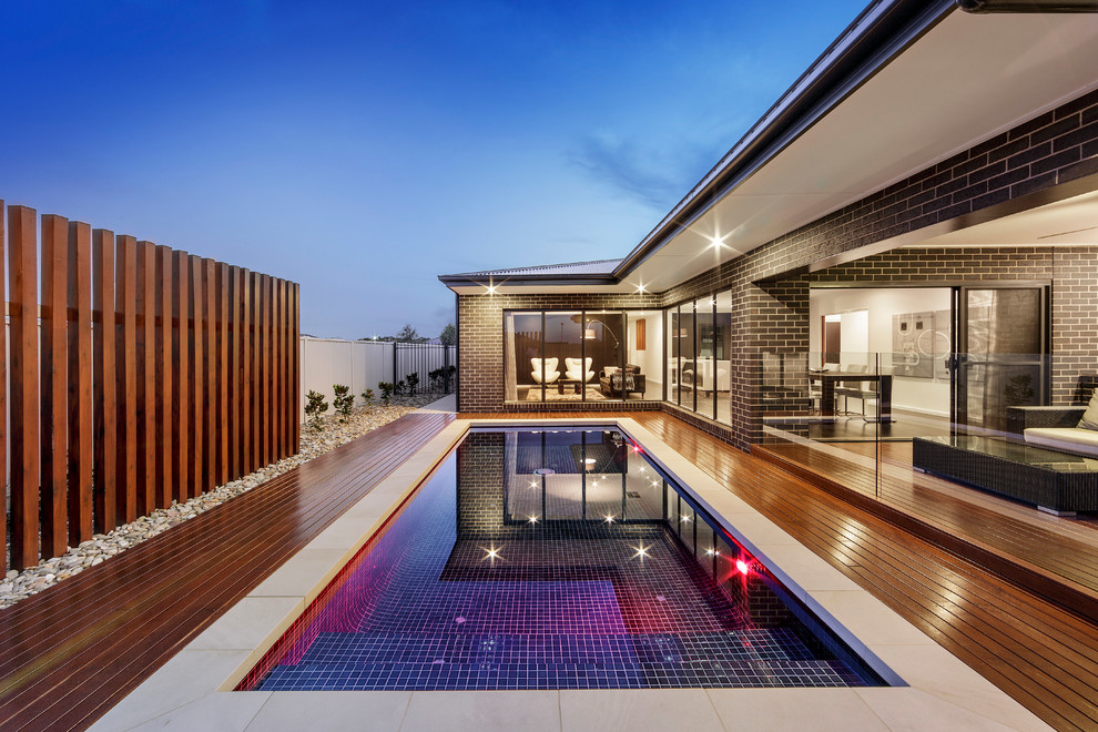 Diseño de piscina alargada moderna pequeña rectangular en patio trasero con entablado