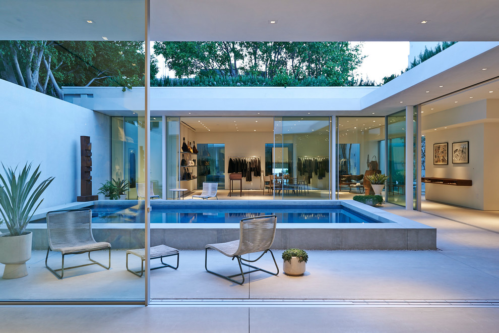 Ejemplo de piscina contemporánea rectangular en patio con losas de hormigón