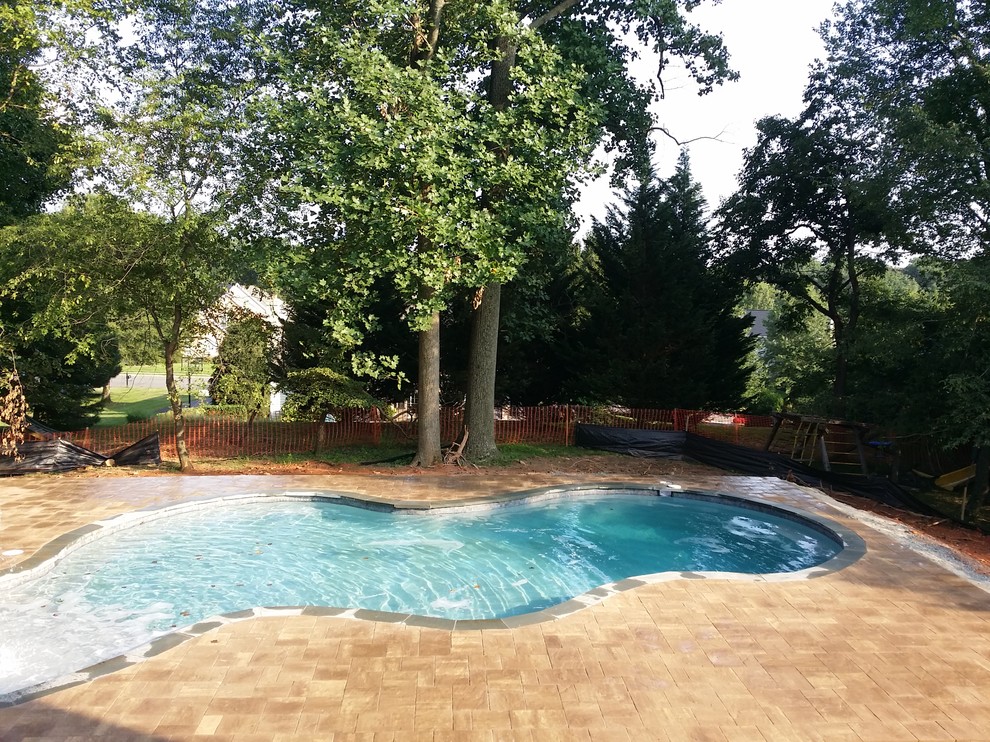 Medium sized classic back custom shaped lengths swimming pool in DC Metro with a water feature and natural stone paving.