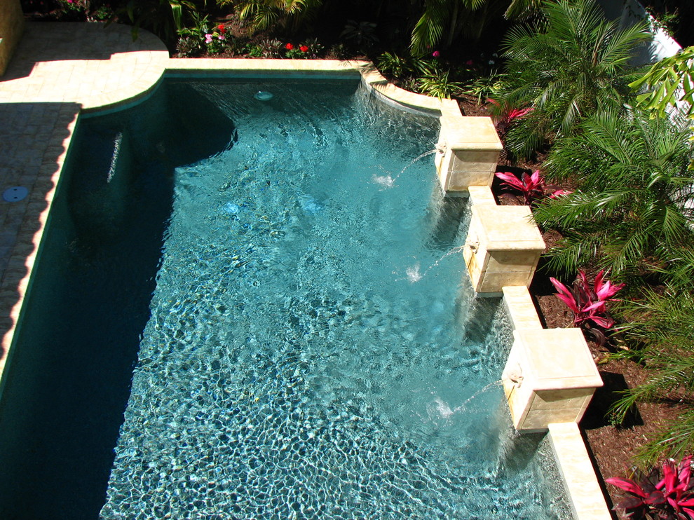 Diseño de piscina con fuente mediterránea de tamaño medio rectangular en patio trasero con adoquines de ladrillo