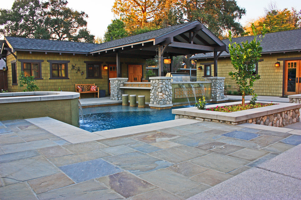 Foto på en stor amerikansk pool på baksidan av huset, med marksten i betong och spabad