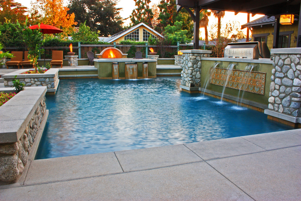 Ejemplo de piscinas y jacuzzis de estilo americano grandes a medida en patio trasero con adoquines de hormigón