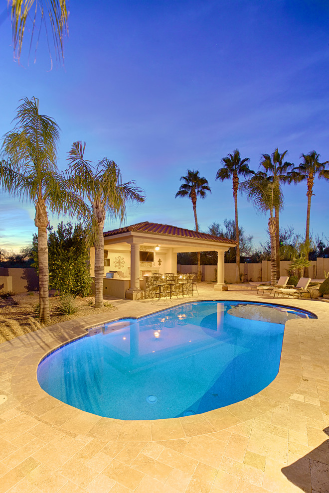Large mediterranean back natural swimming pool in Phoenix with concrete paving.