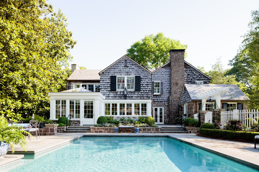 Immagine di una grande piscina monocorsia classica rettangolare dietro casa con una dépendance a bordo piscina e pavimentazioni in pietra naturale
