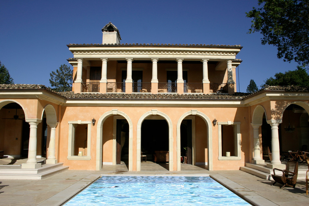 Immagine di una grande piscina mediterranea rettangolare dietro casa con lastre di cemento