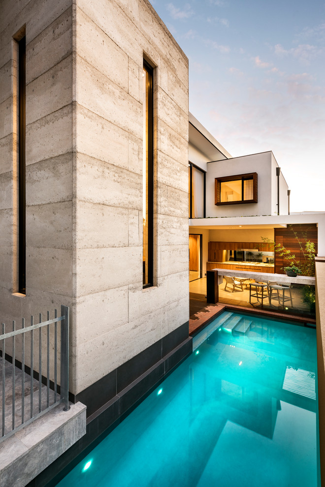 Exemple d'une piscine latérale rectangle avec une terrasse en bois.