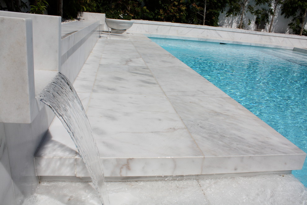 На фото: большой прямоугольный бассейн на заднем дворе в средиземноморском стиле с покрытием из каменной брусчатки с