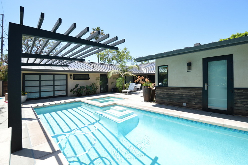 Immagine di una grande piscina monocorsia moderna rettangolare dietro casa con una vasca idromassaggio e lastre di cemento