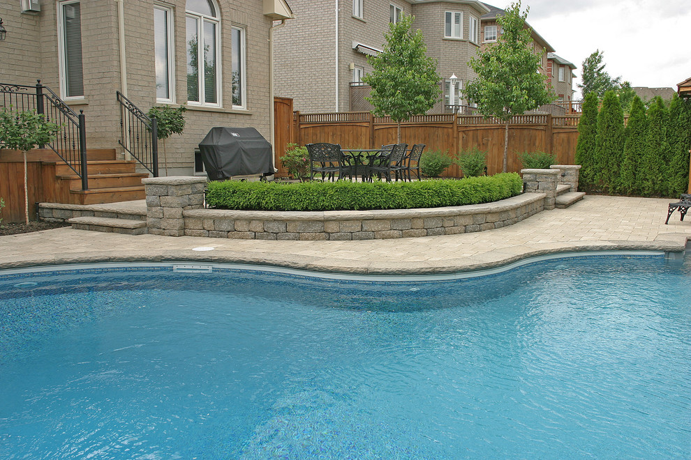 Aménagement d'une piscine arrière classique en forme de haricot de taille moyenne avec des pavés en béton.