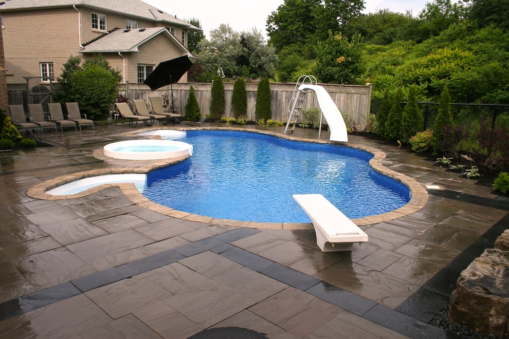 На фото: естественный бассейн среднего размера, произвольной формы на заднем дворе в современном стиле с джакузи и покрытием из каменной брусчатки
