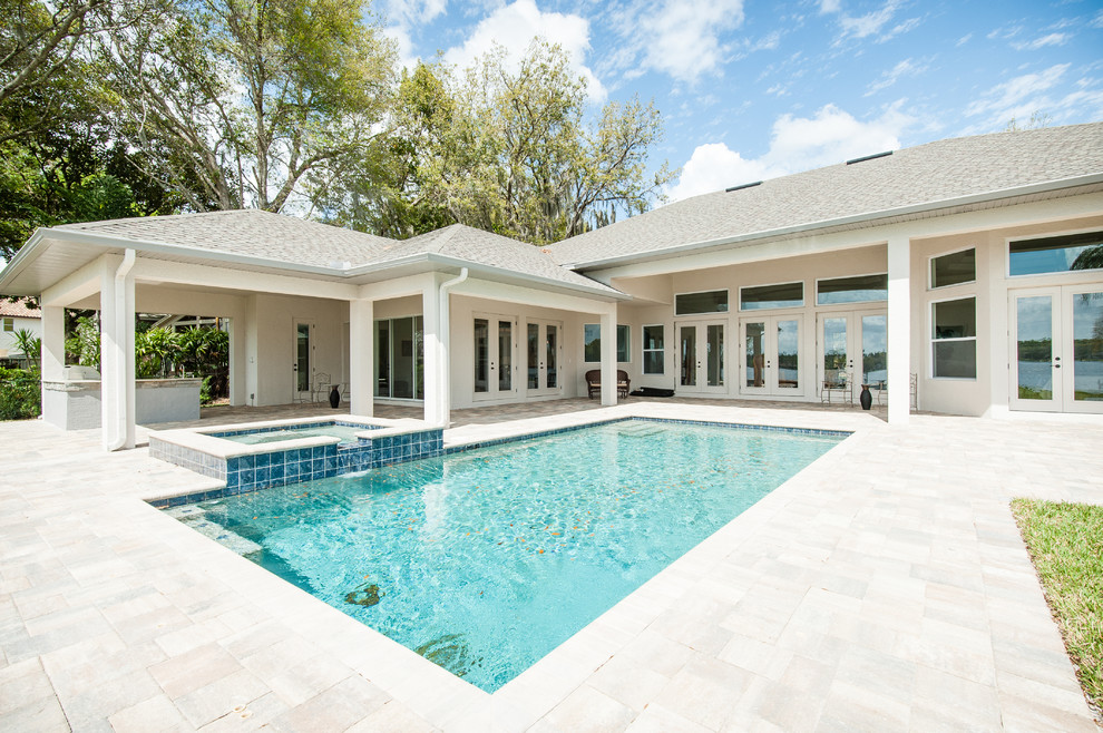 Esempio di una piscina chic rettangolare di medie dimensioni e dietro casa con una vasca idromassaggio e pavimentazioni in mattoni