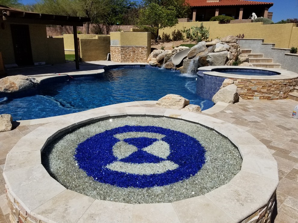 Inspiration for an expansive contemporary back custom shaped lengths swimming pool in Phoenix with a water slide and tiled flooring.
