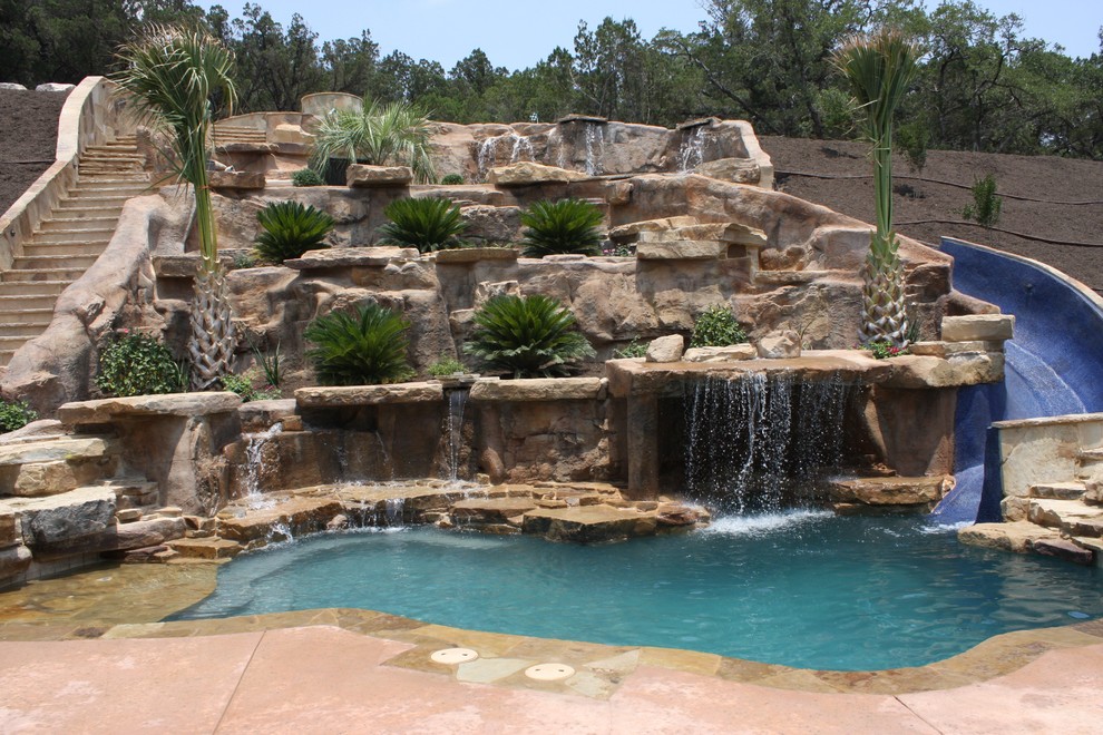 Design ideas for a large contemporary back custom shaped natural swimming pool in Austin with a water slide and decking.