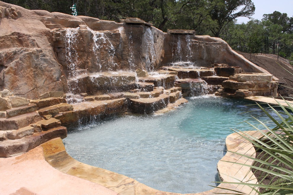 Ispirazione per una grande piscina naturale design personalizzata dietro casa con un acquascivolo e pedane
