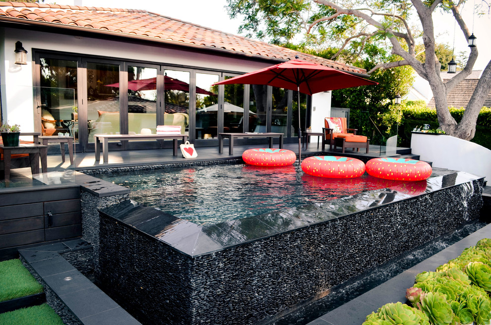 Imagen de piscina con fuente infinita mediterránea de tamaño medio rectangular en patio trasero con entablado