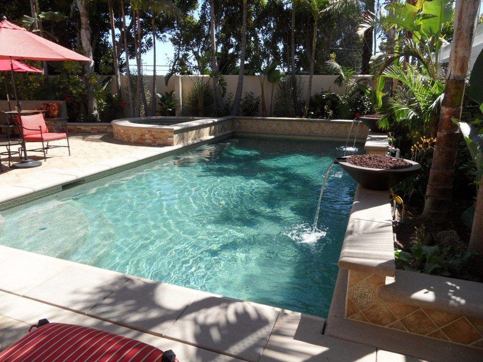 Esempio di una grande piscina monocorsia stile marino rettangolare dietro casa con una vasca idromassaggio e pavimentazioni in pietra naturale